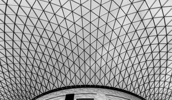 Large darkened auditorium filled with gaming enthusiasts watching a giant screen with neon pink accents, atmospheric crowd lighting, event photography style